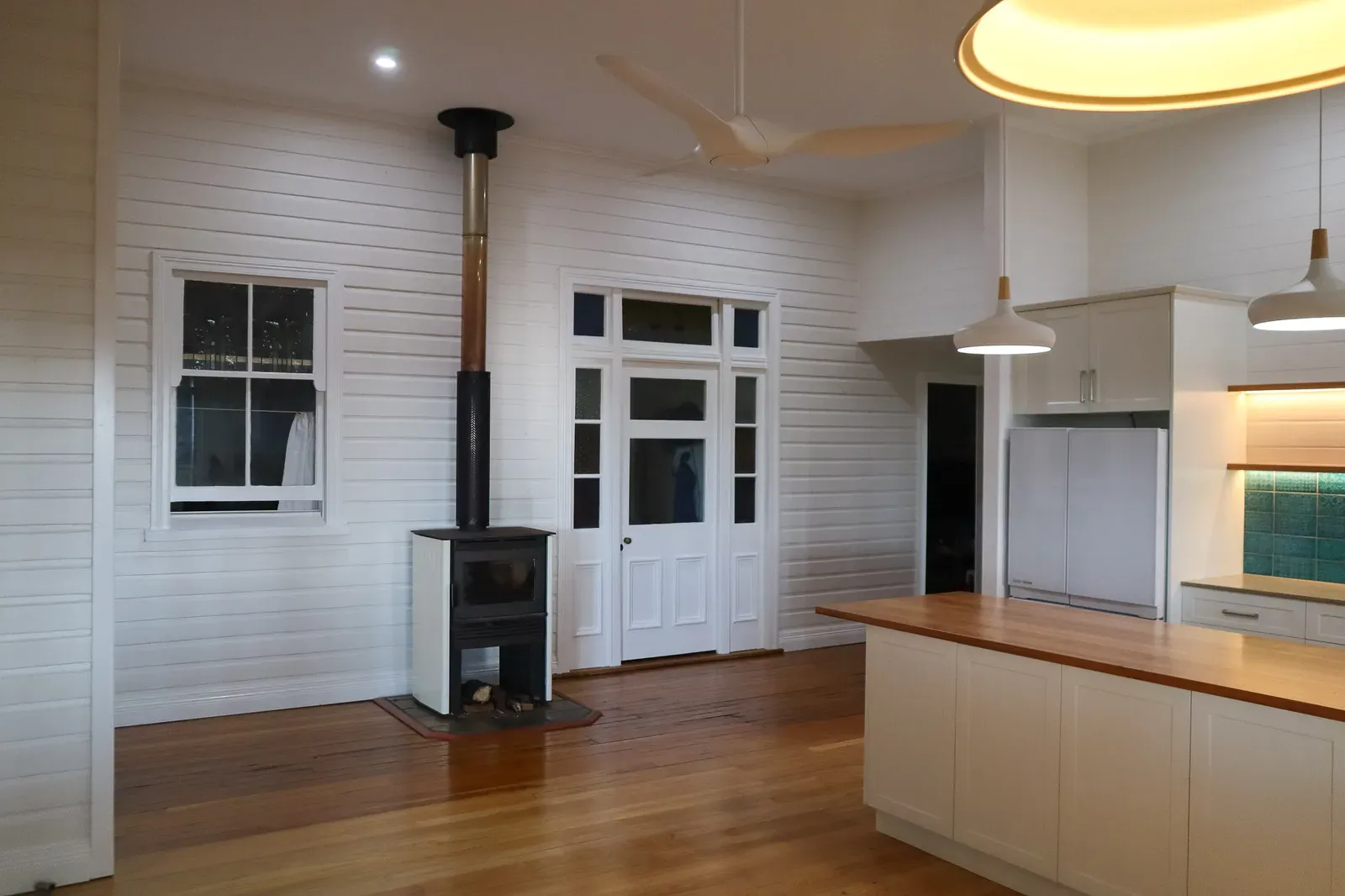 The open-plan kitchen and living area at Cameron Road, with wood heater and timber floors