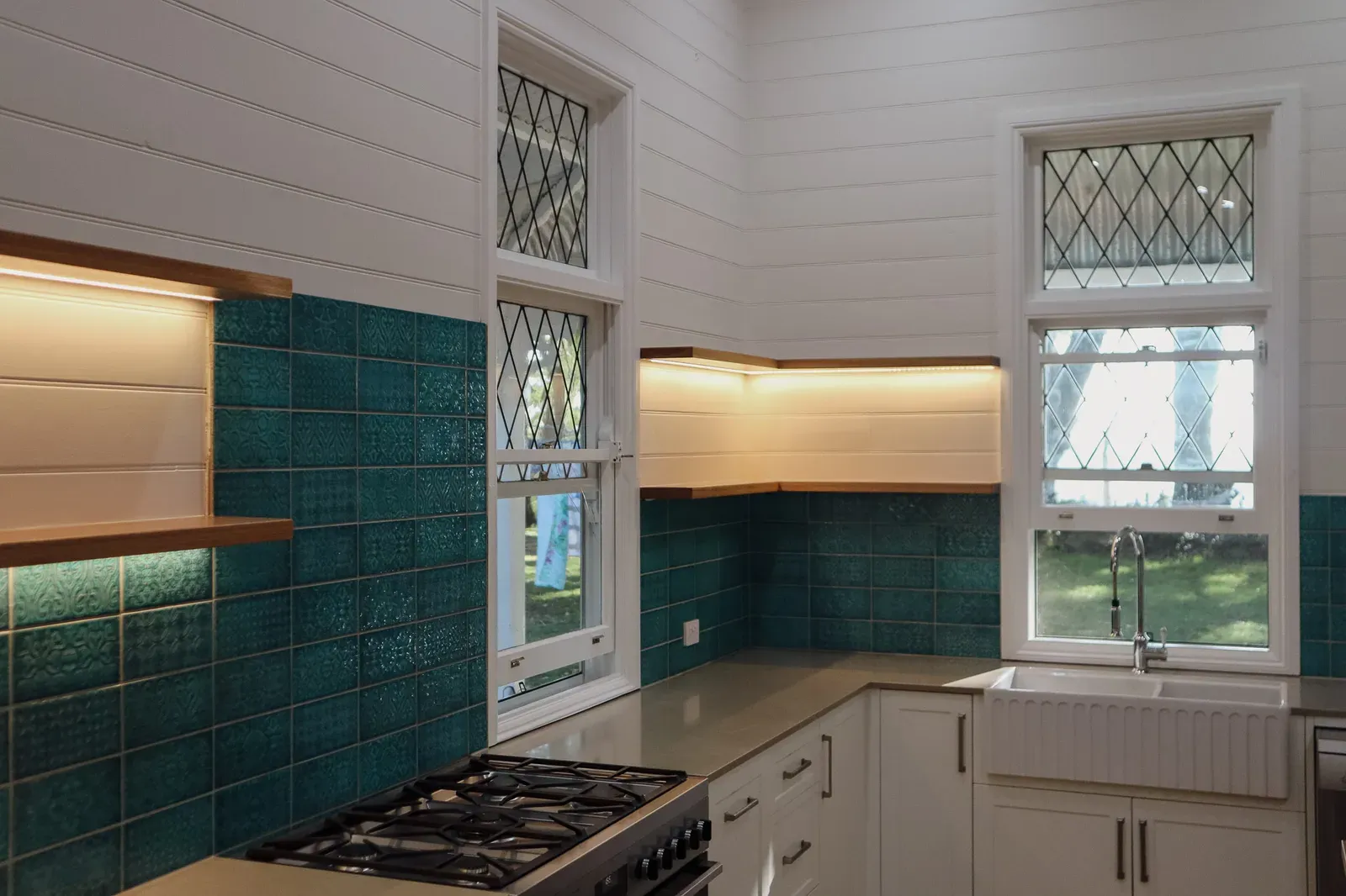 Cooktop, teal tiled splashback and leadlight windows