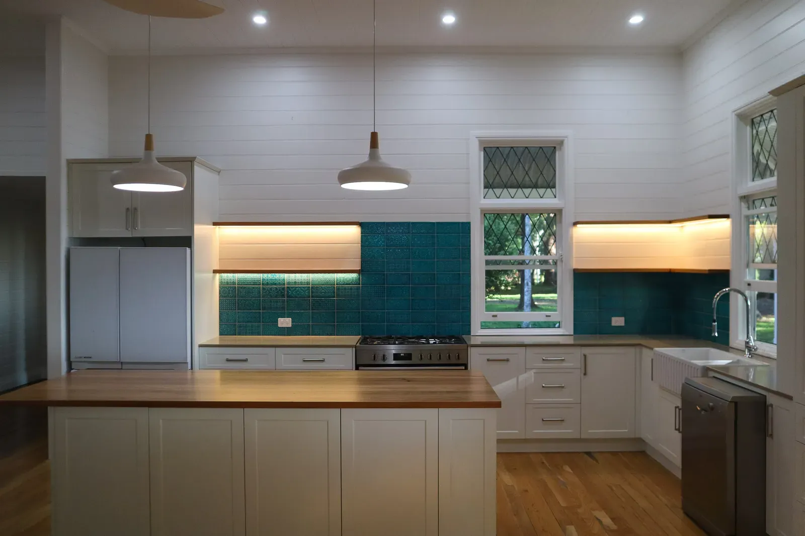 The kitchen with timber benchtops and a teal patterned splashback